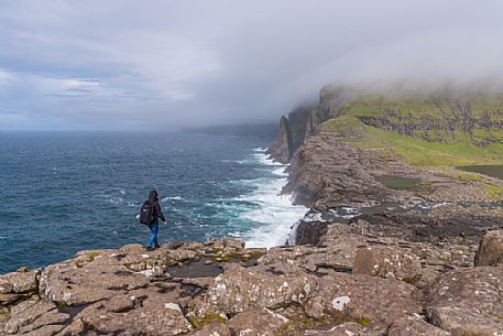 Tourist walkingo on the Srvgsvatn or  Leitisvatn cliffs, Faeroe Islands, Denmark, Europe