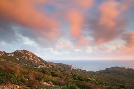 The lighthouse at Cape Teulada taken from an unusual angle, and the coast that is still wild and covered by the typical Mediterranean vegetations, Chia, Domus de Maria, Sulcis-Iglesiente, Sardinia, Italy