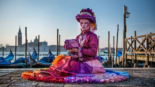 Carnival mask in the San Marco square with gondolas moored in the San Marco basin and the San Giorgio Maggiore church in the background, Venice, Italy, Europe