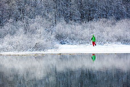 Hiker at Fusine lake in a winter landscape, Tarvisio, Julian Alps, Italy