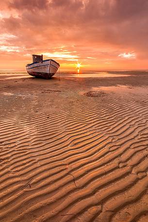 Old boat on Grado beach at sunset, Italy
