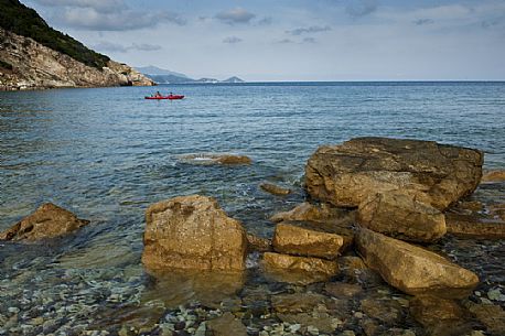 Tourists on a kayak enjoy the crystal clear waters of Cala del Nisportino, Elba island, Tuscany, Italy