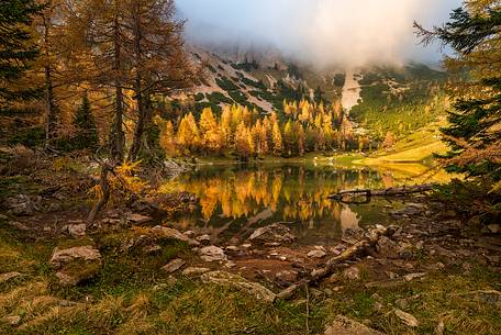 A soft light penetrates the clouds in Bordaglia Lake, Carnia