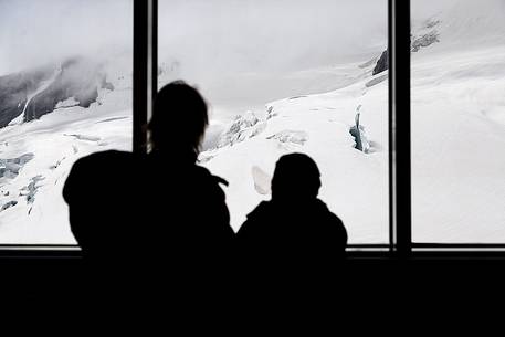 Mother and son inside the Sphinx Observatory on top of the Jungfraujoch, admiring the Aletsch glacier, the largest in Europe, Bernese alps, Switzerland, Europe