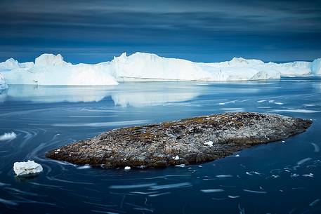 Moving ice in the water of Illulissat Fjord with the first morning light