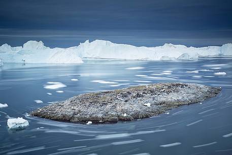 Moving ice in the water of Illulissat Fjord with the first morning light