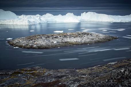 Moving ice in the water of Illulissat Fjord with the first morning light