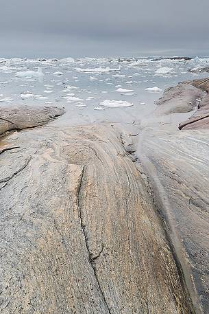 The reefs near the church of Illulissat town: in the background the moving ice of Illulissat Fjord