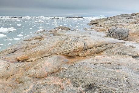 The reefs near the church of Illulissat town: in the background the moving ice of Illulissat Fjord