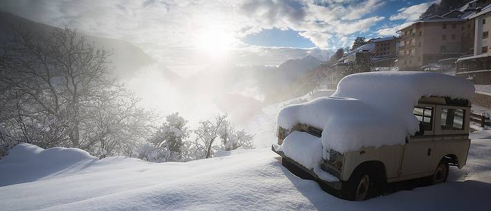 An old Land Rover covered by snow in Casso alpine town after an intense snowfall