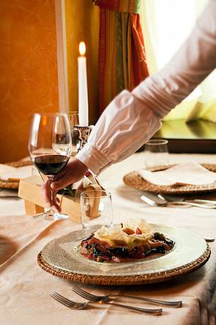 A waitress serving at the table in a typical Alpine restaurant in Sauris di Sotto