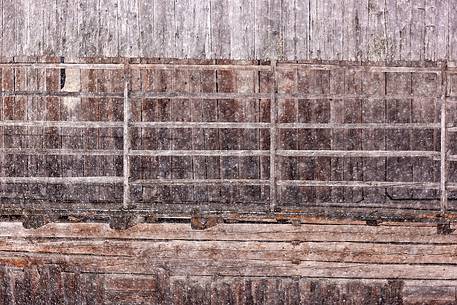 Under a snowfall a typical wooden building in alpine village of Sauris di Sotto