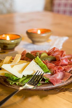 Rustic platter of alpine cheeses and cold cuts of Rinfreddo hut, Comelico, Dolomites, Italy