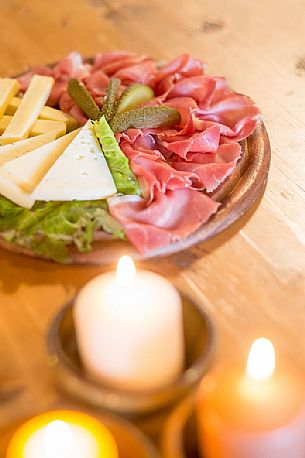 Rustic platter of alpine cheeses and cold cuts of Rinfreddo hut, Comelico, dolomites, Italy