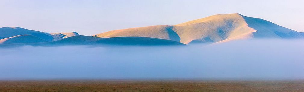 Fog and clouds at dawn on Sibillini meadows, Castelluccio di Norcia, Sibillini National Park, Italy