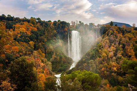 The Marmore waterfall surrounded by woods with autumn colors
