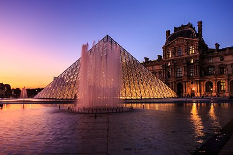 Sunset lights at the Louvre square with the glass pyramid and the fountain, Paris, France, Europe