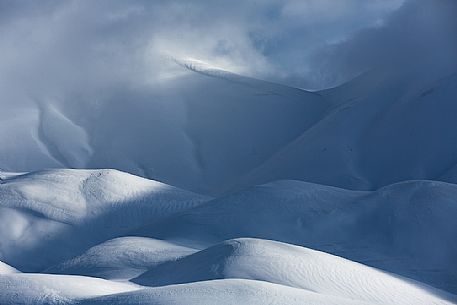 The light that penetrates draws particular shapes on the snowy ground along the road to Mount Prata, Sibillini National Park, Marches, Italy, Europe