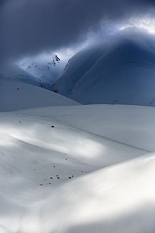 The light that penetrates draws particular shapes on the snowy ground along the road to Mount Prata, Sibillini National Park, Marches, Italy, Europe