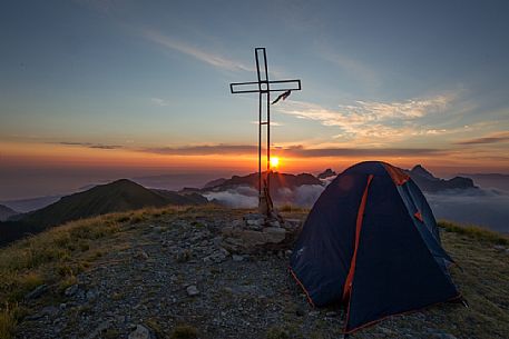 Sunset with tent in the peak of Apuane Alps from Penna di Sumbra mountain peak, Tuscany, Italy, Europe