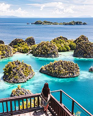 Woman enjoying the landscape from the scenic viewpoint in Piaynemo, one of the Raja Ampat archipelago most popular tourist spots, West Papua, New Guinea, Indonesia.