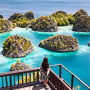 Woman enjoying the landscape from the scenic viewpoint in Piaynemo, one of the Raja Ampat archipelago most popular tourist spots, West Papua, New Guinea, Indonesia.