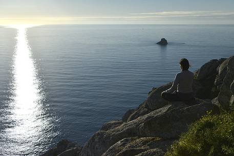 Young woman awaiting for sunset at Cape Fisterra or Finisterre, La Corua, Galicia, Spain, Europe