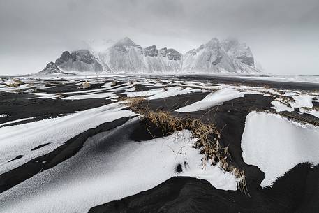 Black and white dunes on beach after blizzard. Stokksens mountain in background.