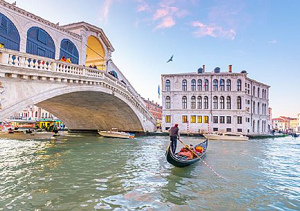 Gondola tourists in the  Canal Grande near Rialto Bridge, Ponte di Rialto in the background at sunset, Venice, Italy, Europe