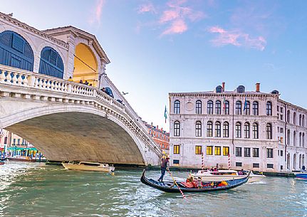 Gondola tourists in the  Canal Grande near Rialto Bridge, Ponte di Rialto in the background at sunset, Venice, Italy, Europe